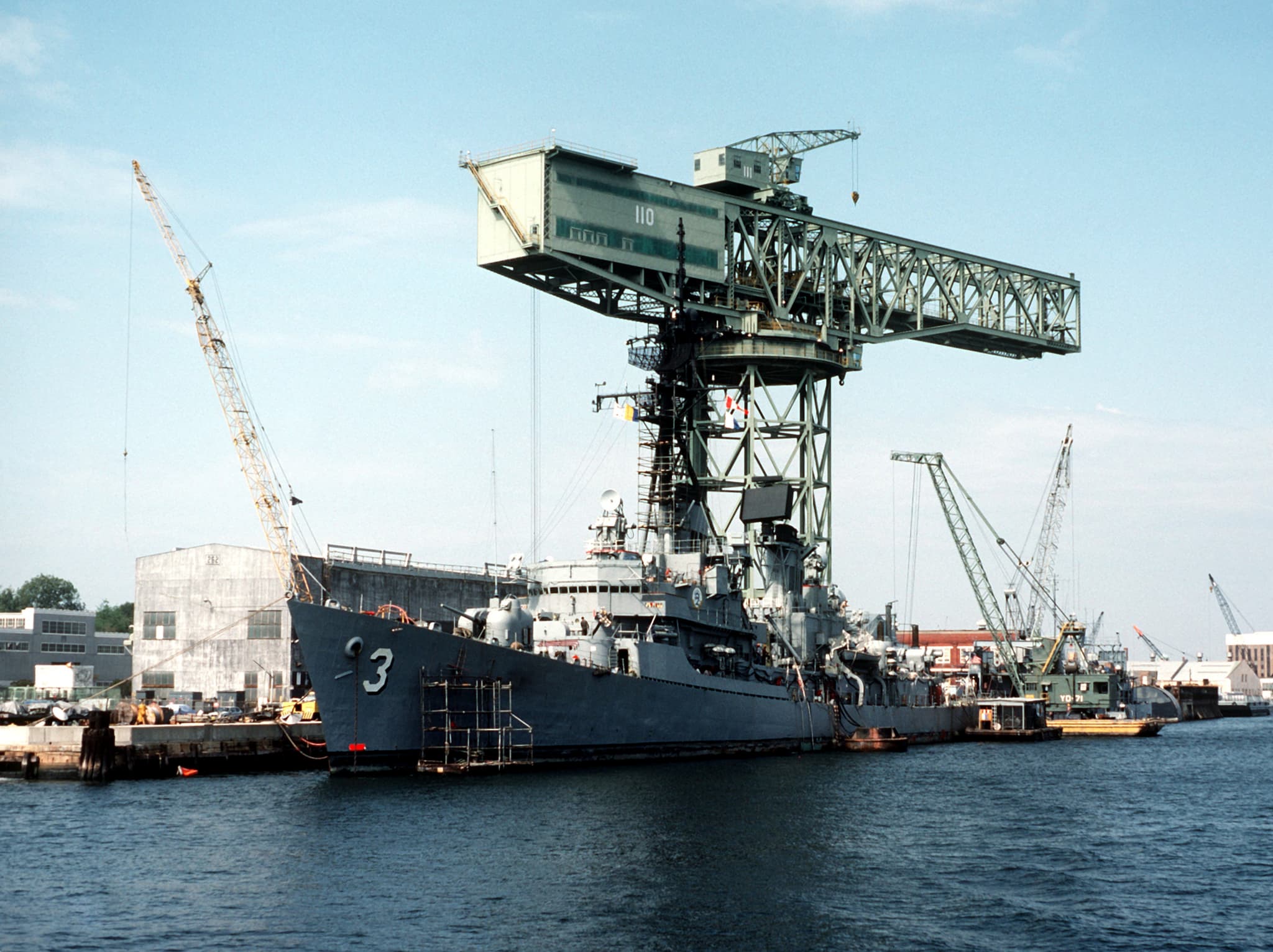 USS John King (DDG-3) in drydock at Norfolk Naval Shipyard, with the signature hammerhead crane behind.