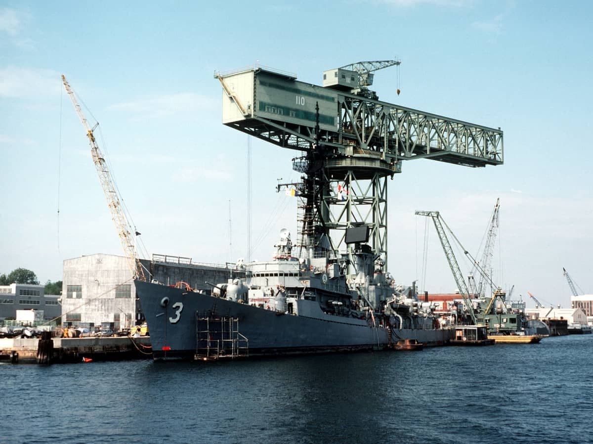 USS John King (DDG-3) in drydock at Norfolk Naval Shipyard, with the signature hammerhead crane behind.